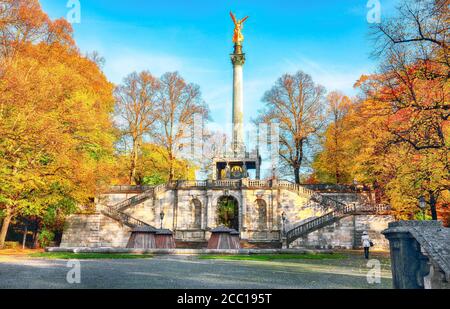 Reizvolle Herbstansicht des Friedensengel-Denkmals. Statue eines goldenen Engels auf einer Säule im Stadtpark. Standort: München, Bayern, Deutschland Stockfoto