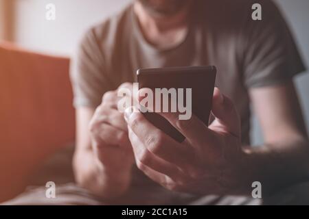 Mann, der zu Hause ein Mobiltelefon benutzt, Nahaufnahme von männlichen Händen, die dem Smartphone verfallen, selektiver Fokus Stockfoto