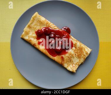 Pfannkuchen mit Kirschmarmelade. Auf einem großen grauen Teller Stockfoto