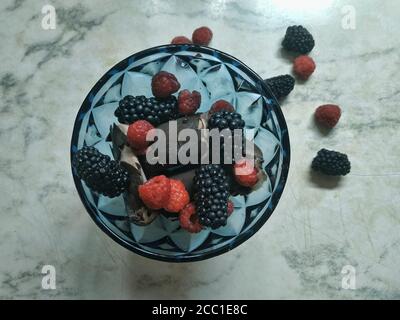 Schokoladeneis mit Brombeeren und Himbeeren im Dunkeln Blauer Eiskegel Stockfoto