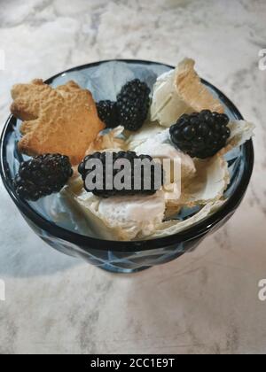 Eis mit Brombeeren und Keksen in dunkelblau Eiskonus Stockfoto
