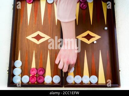 Frauenhand spielt Backgammon - traditionelles altes Brettspiel. Schöne alte elegante Mahagoni Holz Spiel Stockfoto