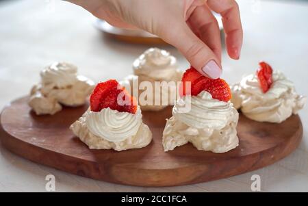 Der Prozess, Pavlova Dessert zu kreieren und das Meringue mit Sahne aus der kulinarischen Tasche zu schmücken Stockfoto