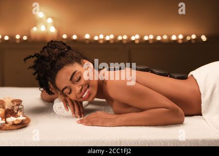 Schwarze junge Frau bekommen heißen Stein Massage im Spa Stockfoto