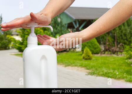 Desinfizierende Frauen Hände Desinfektionsmittel aus einer weißen Flasche Nahaufnahme. Das Konzept der passiven Schutz gegen Viren und Krankheiten in covid Zeit. Stockfoto