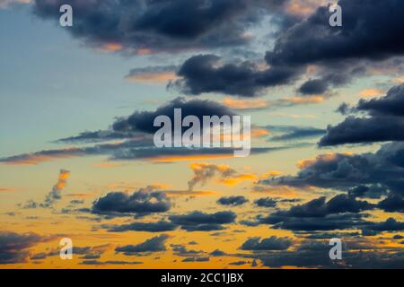 Ein sehr dramatischer Himmel voller Gelb, Blau und Orangen. Kontrastierende Wolken während des Sonnenuntergangs von der untergehenden Sonne beleuchtet. Hell gesättigt natürlich Stockfoto