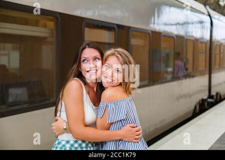 Glückliche junge Frauen stehen auf dem Bahnhofsplatz Stockfoto