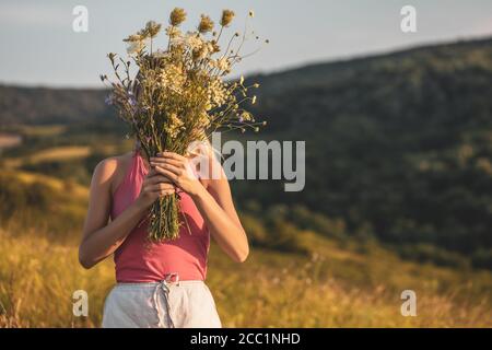 Frau hält Blumenstrauß und genießt in der Natur. Stockfoto