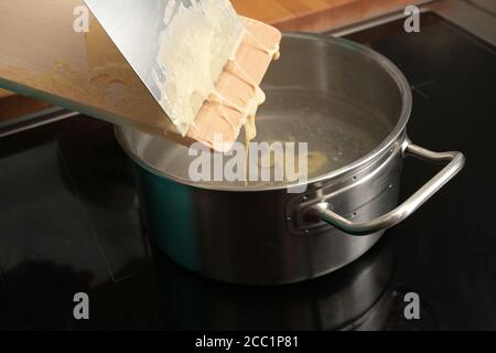 Kochen spätzle, hausgemachter Eiernudelteig wird von einem Holzbrett in kochendes Wasser geschabt, typisches Gericht in Schwaben, Süddeutschland und Österreich, Stockfoto