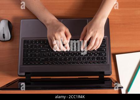 Menschliche Hände tippen Text auf einer schwarzen Laptop-Tastatur. Stockfoto