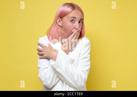 Frau in weißer Jacke bedeckt Mund mit Hand Blick auf Etwas Stockfoto