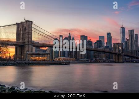 Farbenprächtiger rosa Sonnenuntergang hinter der Brooklyn Bridge und New York Skyline Stockfoto