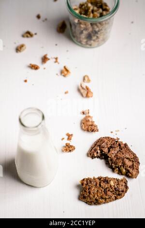 Glas Milch mit zerbrochenen Keksen und Walnüssen im Glas, Nahaufnahme Stockfoto