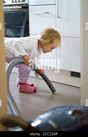 Deutschland, Kiel, Mädchen Reinigung Küche mit Staubsauger Stockfoto