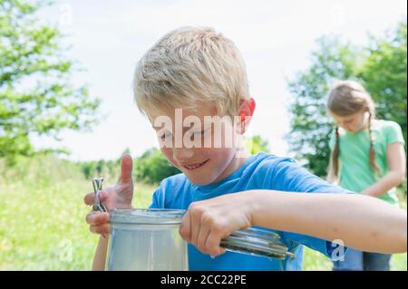 Deutschland, Bayern, München, Boy Holding Glas während Mädchen im Hintergrund Stockfoto