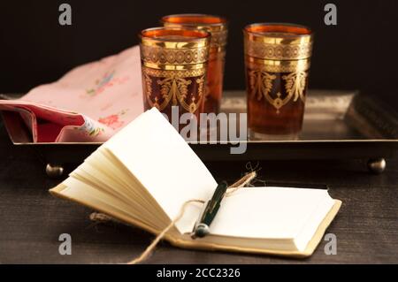 Schwarzer Tee mit Buch auf Holztisch, Nahaufnahme Stockfoto