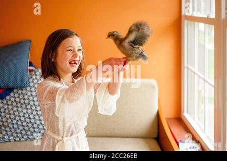 Ein lachendes Kind mit fehlendem Zahn hält einen flatternden Vogel Hoch Stockfoto