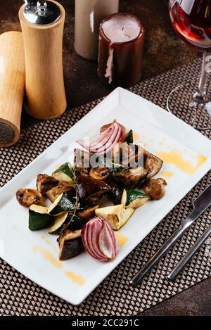 Gegrilltes Gemüse auf einem weißen Teller mit einem Glas Wein Stockfoto