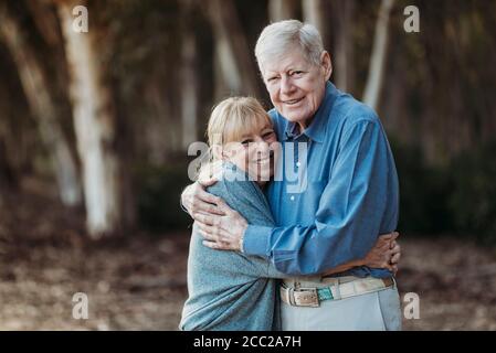 Portrait eines erwachsenen Rentnerpaares, das sich im Wald umarmt Stockfoto