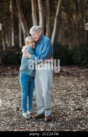 Portrait eines älteren erwachsenen Ehepaares im Ruhestand, das sich im Wald umarmt Stockfoto