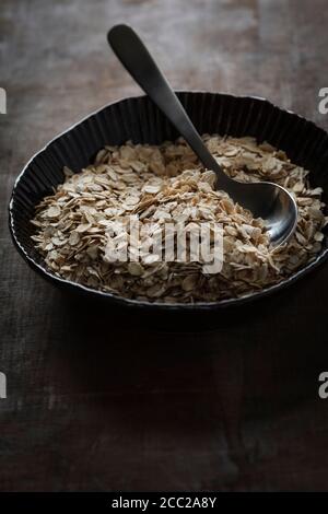 Schüssel von Haferflocken mit Löffel auf Tisch, Nahaufnahme Stockfoto