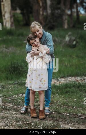 Großmutter und Enkelin umarmen und lächeln im Feld Stockfoto