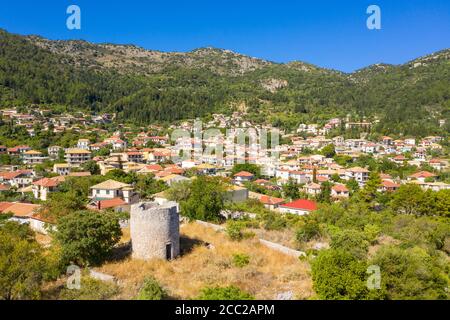 Eine zerstörte Windmühle mit Gebäuden hinter Karya, einem traditionellen Bergdorf in Lefkada, Ionische Inseln, Griechenland Stockfoto