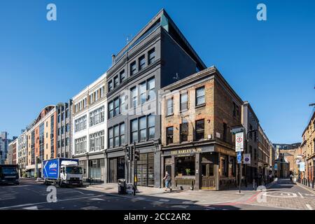 Schräge horizontale Ansicht von Curtain Road nach Südosten zu Rivington Street, mit Sonne auf der Höhe. Das Gerstenmähen, ein Wahrzeichen im Osten Londons Stockfoto