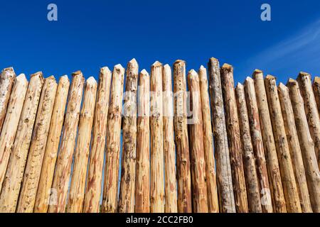 Holzzaun aus geschärften gehobelten Stämmen. Stockfoto