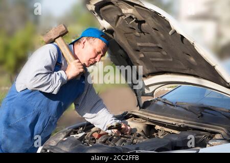 Überraschender Mechaniker schaut in das Auto. Stockfoto