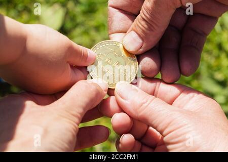 Hände von verschiedenen Menschen mit einer Goldmünze Bitcoin. Unscharfer Hintergrund. Stockfoto