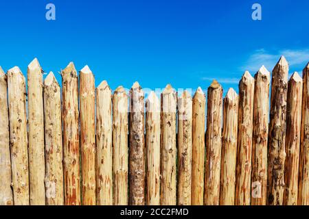 Holzzaun aus geschärften gehobelten Stämmen. Stockfoto