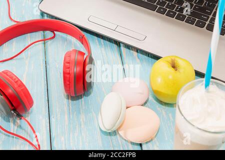 Offener Laptop mit weißer Tasse Kaffee, Marshmallows und roten Kopfhörern. Stockfoto