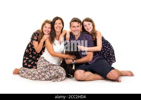 Horizontales Porträt einer jungen Familie mit ihrem Hund vor weißem Hintergrund in einem Studio oder High-Key. Stockfoto