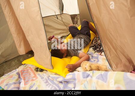 Cedar Rapids, Iowa, USA. August 2020. 16. August 2020: Mitglieder der Phillips und Salvador Familien hängen in ihren Zelten und behelfsmäßigen Wohnräumen außerhalb ihrer Wohnung. Cedar Terrace Apartments, eine Gemeinschaft von vielen, die Flüchtlinge in ihrem eigenen Land waren, wurde während des Sturms, der die Gegend am Montag, den 10. August heimgesucht hatte, verschlingt. Viele der Gebäude sind verurteilt, so dass die Bewohner draußen in Zelten schlafen. Nachdem die Lokalnachrichten erschienen sind, kommen Spenden und die Feuerwehr versucht, so viele wie möglich in Unterstände zu stecken. Leider weigern sich viele von ihnen zu gehen Stockfoto