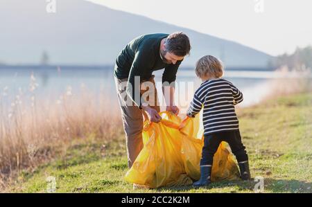 Vater mit kleinen Sohn sammeln Müll im Freien in der Natur, plogging Konzept. Stockfoto