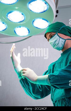 Professioneller Chirurg Arzt Vorbereitung und Tragen von chirurgischen Handschuhen an den Händen vor der Operation in er-Operationssaal im Krankenhaus. Stockfoto
