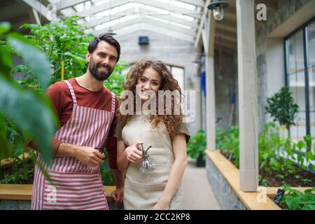 Porträt eines Gärtners, der im Gewächshaus steht und die Kamera anschaut. Stockfoto