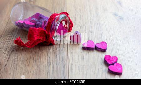 Rosa Herzen kommen aus Glasflasche auf Holztisch Stockfoto