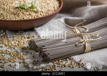 Ländliche Stillleben - traditionelle japanische Soba-Nudeln aus Buchweizenmehl und die geschälten Grütze aus Buchweizen, auf dem Hintergrund von Sackleinen, Nahaufnahme Stockfoto