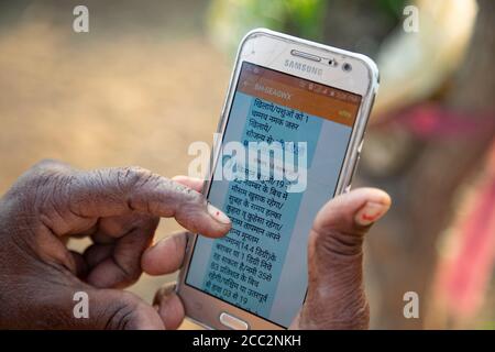 Eine ältere Frau liest eine Textnachricht, die sie auf ihrem Mobiltelefon als Teil des Frühwarnsystems, das vom LWR Transboundary Flood Resilience Project eingerichtet wurde, erhalten hat. Solche Textnachrichten werden an die Bewohner der Gemeinden in den Gandak und Koshi Flusseinzugsgebieten gesendet, damit sie genaue Informationen über die Wetterprognosen und die Hochwasserpegel stromaufwärts erhalten. Stockfoto