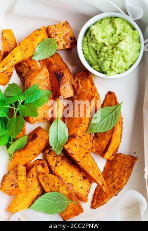 Gebackene Süßkartoffelkeile mit Avocado-Dip. Gesundes veganes Lebensmittelkonzept. Stockfoto