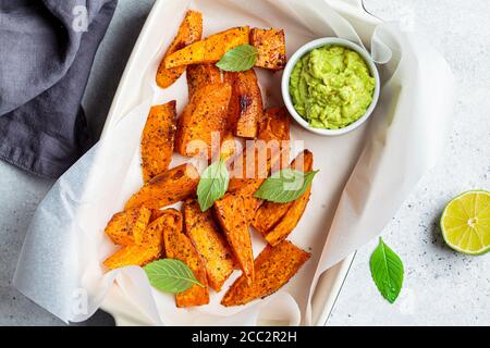 Gebackene Süßkartoffelkeile mit Avocado-Dip. Gesundes veganes Lebensmittelkonzept. Stockfoto