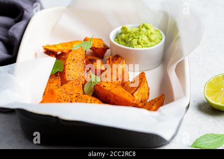 Gebackene Süßkartoffelkeile mit Avocado-Dip. Gesundes veganes Lebensmittelkonzept. Stockfoto