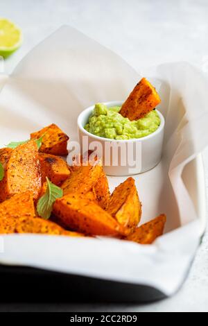 Gebackene Süßkartoffelkeile mit Avocado-Dip. Gesundes veganes Lebensmittelkonzept. Stockfoto