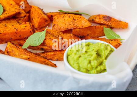 Gebackene Süßkartoffelkeile mit Avocado-Dip. Gesundes veganes Lebensmittelkonzept. Stockfoto