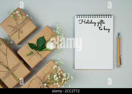 Schöne Ferienwohnung legen minimale Zusammensetzung mit Holzstift, Notizbuch und Geschenk-oder Geschenkschachteln, mit Kraftpapier auf grauem Hintergrund mit eingewickelt Stockfoto