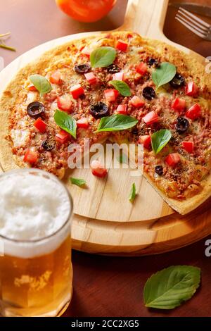 Glas Chopp leckere Pizza mit Oliven und geriebenen Pepperoni Auf Holzbrett Stockfoto