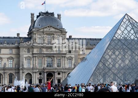 Louvre Museum Paris mit Besuchern an hellen sonnigen Tag. Menschen stehen in der Schlange oder nehmen Selfies. Paris - Frankreich, 31. Mai 2019 Stockfoto