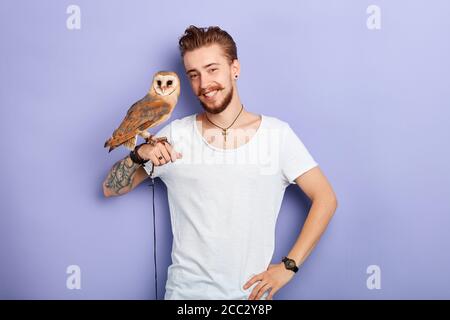 Heiter positiv schöner Mann mit einem schönen auf den Armen Blick auf die Kamera. Tierliebhaber, Nahaufnahme Porträt, isoliert blauen Hintergrund, Studio s Stockfoto